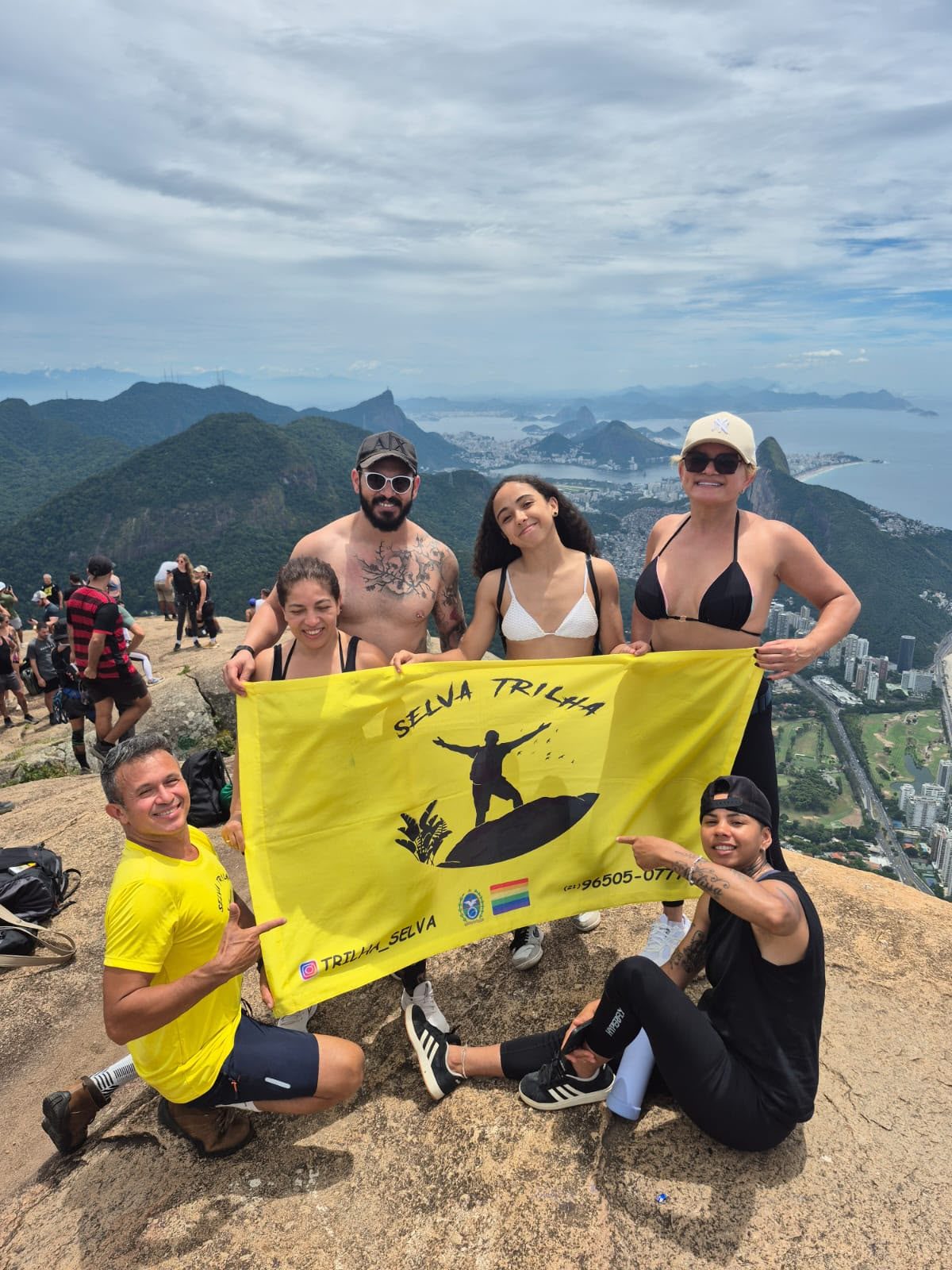 Grupo de trilheiros no alto da montanha com a bandeira da equipe